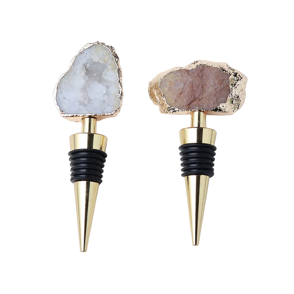 Two wine bottle stoppers with natural stone tops and gold bases on a white background