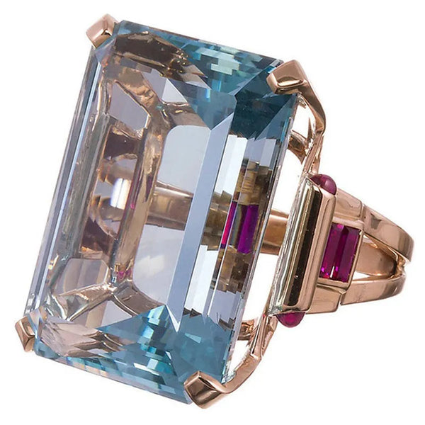 This Aquamarine Cubic Cocktail Ring is a large dreamy rectangle ring. It is crafted with a rich aquamarine and rose gold tone hue. A statuesque blue crystal like stone in the centre.