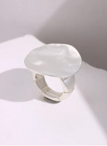 Silver ring with a large, smooth stone on a white surface