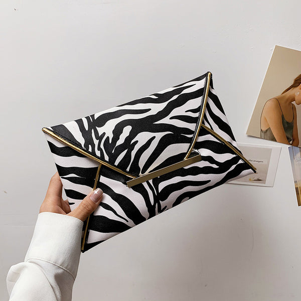 The Snake Pattern Envelope Clutch Sis a flat, lined envelope clutch bag with colored alligator snake pattern. Magnetic metal tab closure. In 100 Percent PU eco leather.